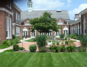 1 A landscaped courtyard with a fountain, surrounded by a brick building with white trim and a cupola.