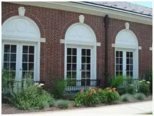 5 Arched windows on a brick building with landscaping in front.