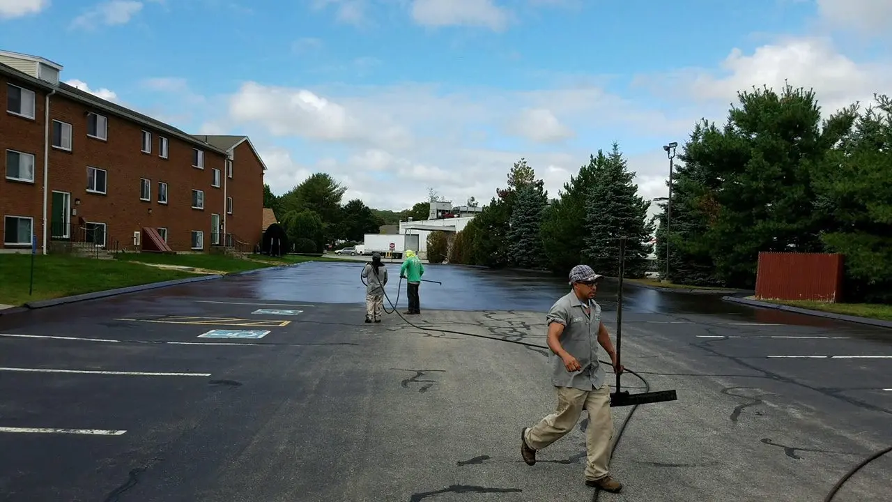 Workers apply sealant to a parking lot.