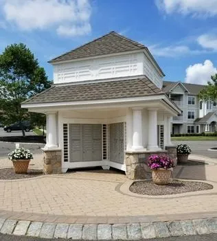 Elegant small pavilion with stone pillars and potted flowers on a brick pathway.